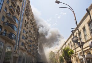 street view of an 8 story residential building with smoke coming from the roof.