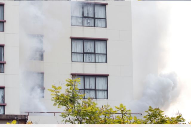 Apartment building with smoke coming out of windows.